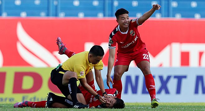 Referee assisting a player after a collision in a match to prevent tongue swallowing.