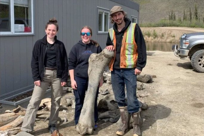 3 miners beside one of the "beast" bones they found