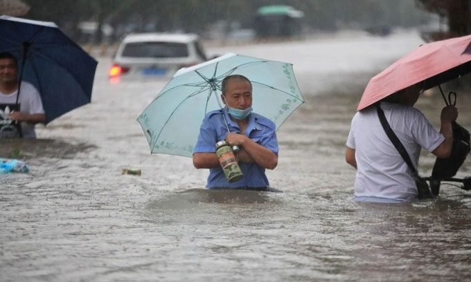 Residents wade through floodwaters in Zhengzhou.