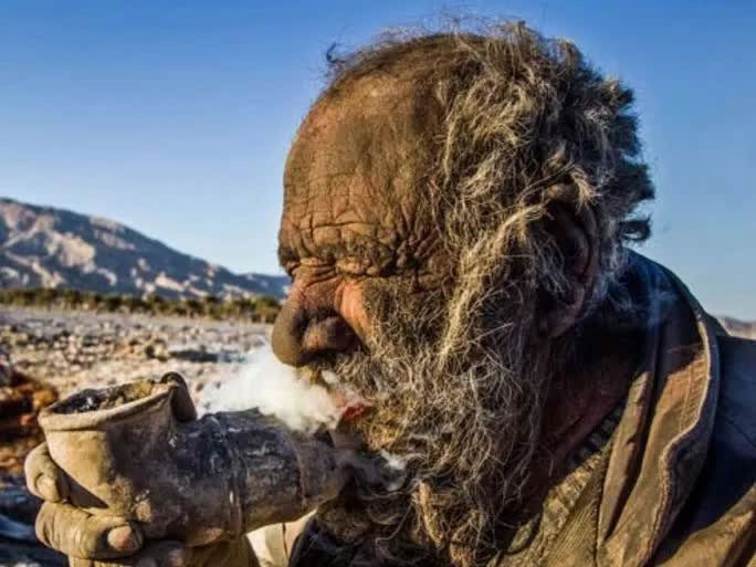 Mr. Haji smoking a pipe filled with animal feces.