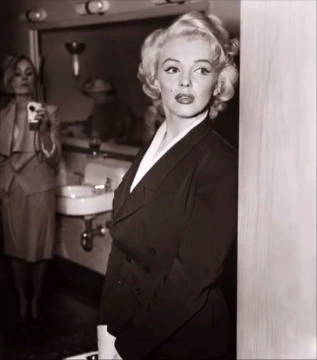 The woman behind Marilyn Monroe holding an object resembling a modern camera.