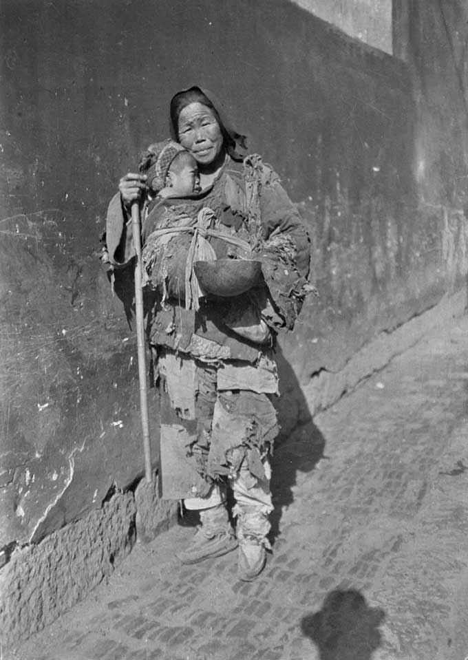 A woman carrying a child begging on the streets, in Zhejiang.