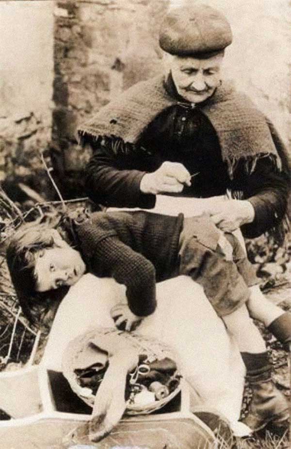 Grandmother mending the only pair of pants for her grandson, photo taken in 1907