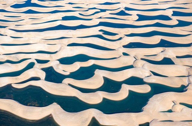 White sand dunes interspersed with small emerald lakes.