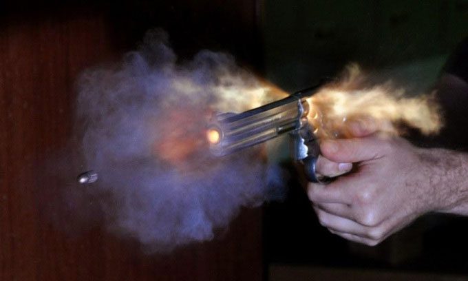 A high-speed photo shows a bullet firing from a handgun.