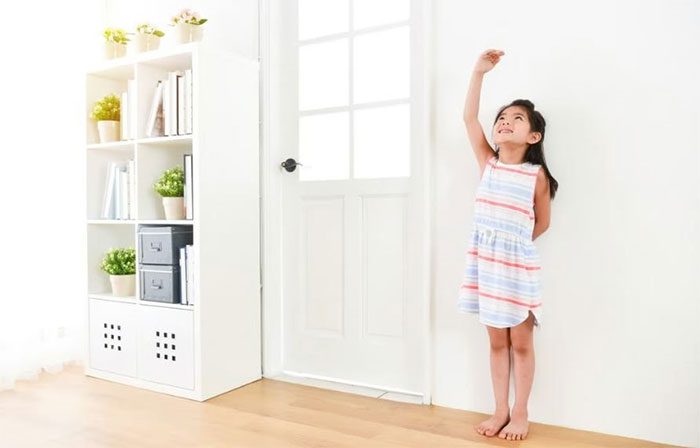 A girl measuring her height with her hand