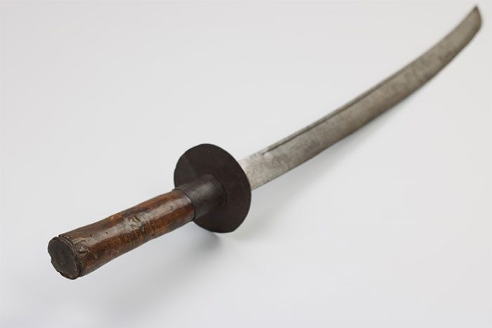 The sword features a round disc-shaped guard and a wooden handle.