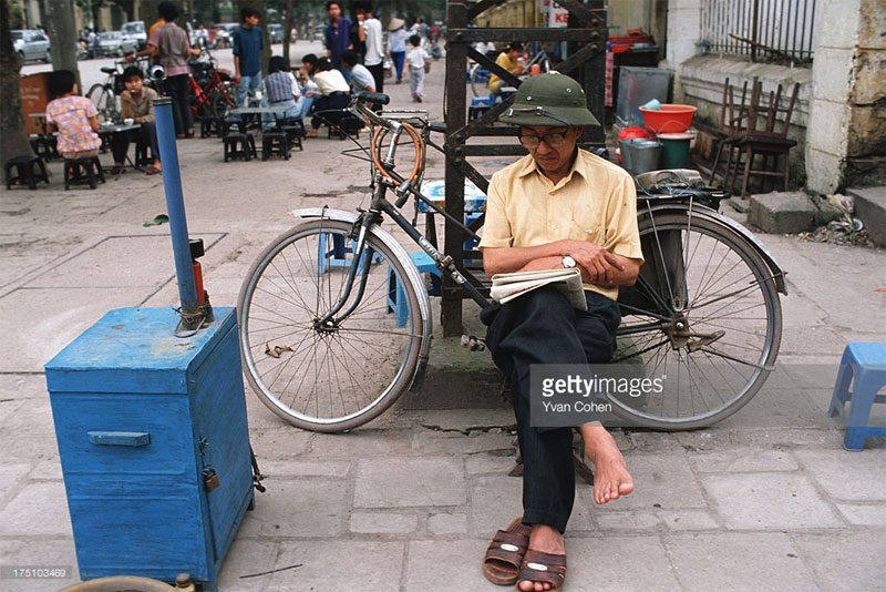 A mechanic reading a newspaper on Trần Hưng Đạo Street.