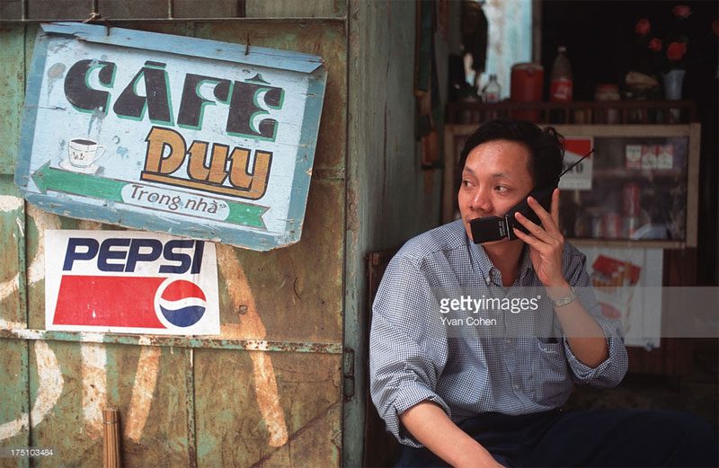 A man talking on a mobile phone at a sidewalk café.