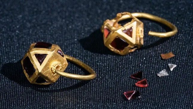 A pair of gold earrings inlaid with red stones, possibly garnet or agate.