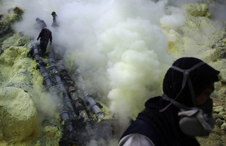 Miners break the cooled sulfur blocks and place them in baskets.