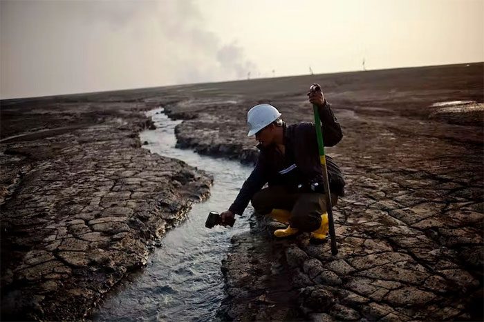 An employee in Sidoarjo testing the water temperature near the Lusi mud volcano in 2011.