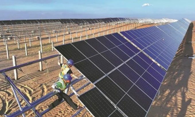 Workers installing photovoltaic panels in the Kubuqi Desert.