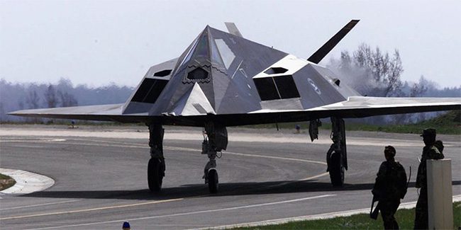 Two U.S. soldiers stand next to an F-117 stealth aircraft at Spangdahlem Air Base