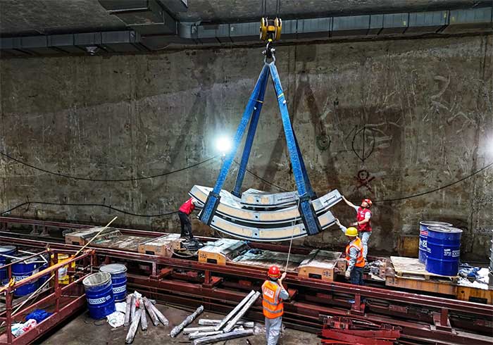 In the opposite direction, cranes lower concrete tunnel lining panels into the underground station.