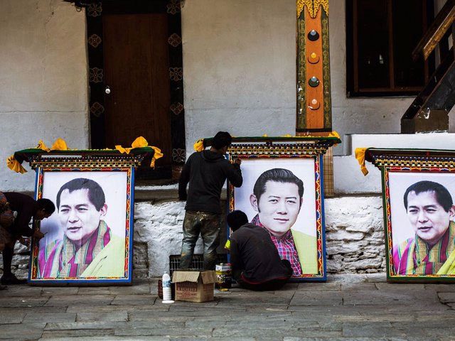 Workers preparing portraits of the former king of Bhutan