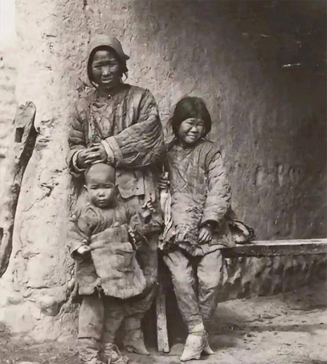 In the biting cold wind, a mother and her two children appear sorrowful.