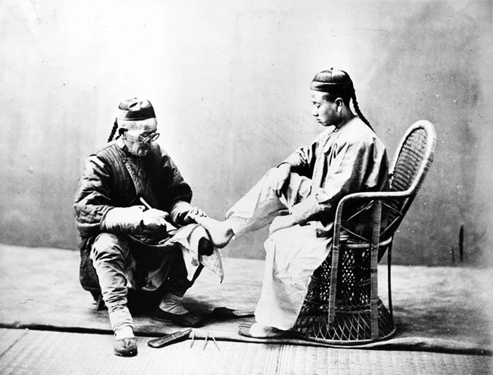 A man trimming nails on the street in 1875.