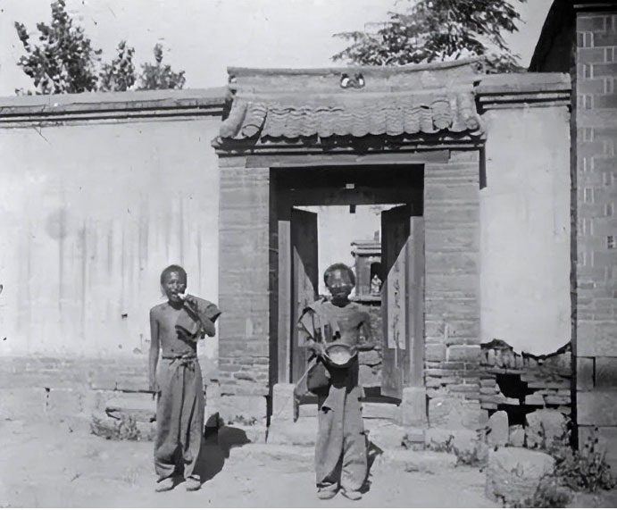 Two beggars display their 'harvest' after exiting a house.