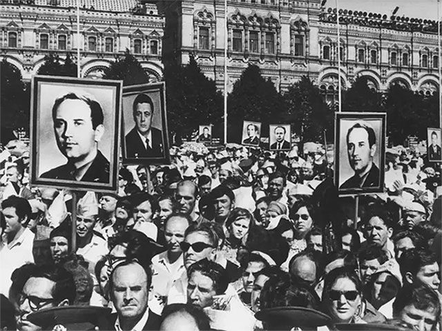 A crowd marches through Red Square in Moscow to commemorate the deaths of three astronauts.