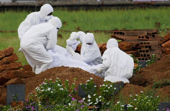 Healthcare workers bury the body of a patient who died from the Nipah virus