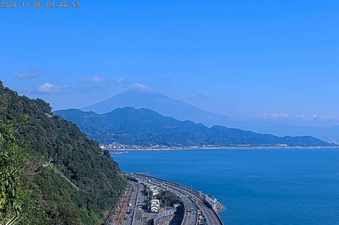 Mount Fuji (on the left) covered in a layer of snow at its summit as seen from the city of Shizuoka.