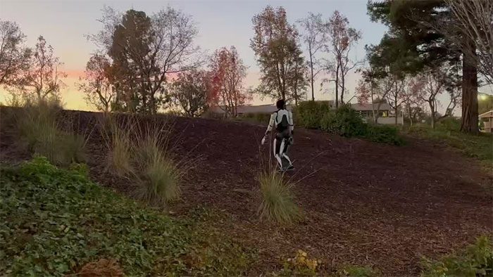 Optimus robot navigating steep, gravel-covered terrain.