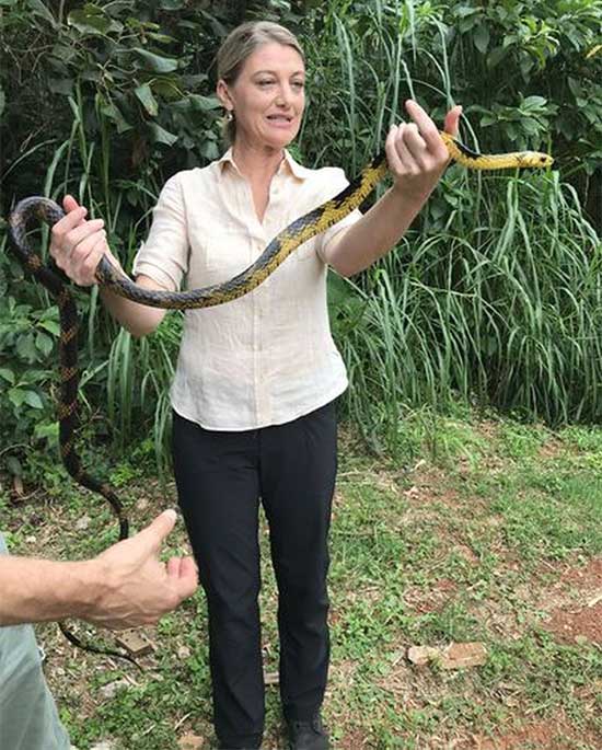 Tara Brown takes a photo with a snake during her visit to the island.