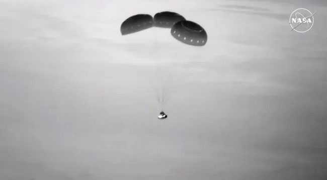 Boeing's Starliner spacecraft parachuting down from above.