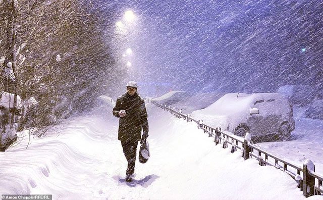 A snowstorm does not deter a man walking through downtown Murmansk.