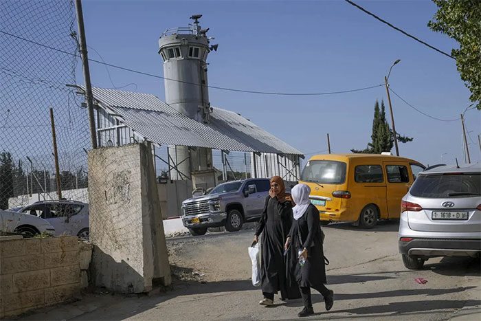 Two Palestinians walking past the aforementioned Israeli military watchtower.