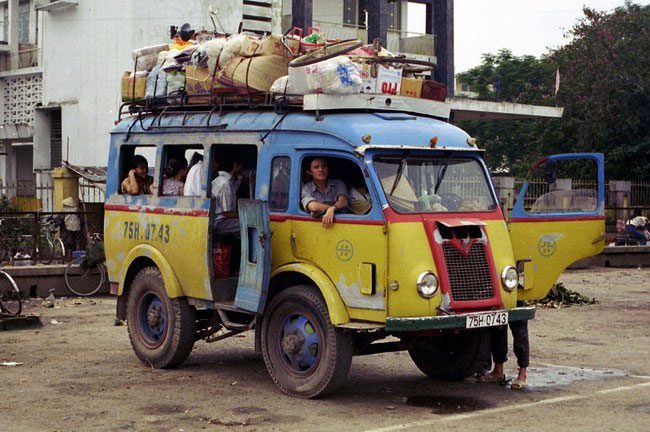 The vintage bus with license plate 75H-07-43 looks "overloaded" as it prepares to depart.