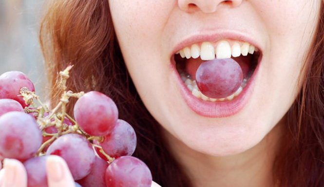 A girl eating grapes for luck in the New Year.