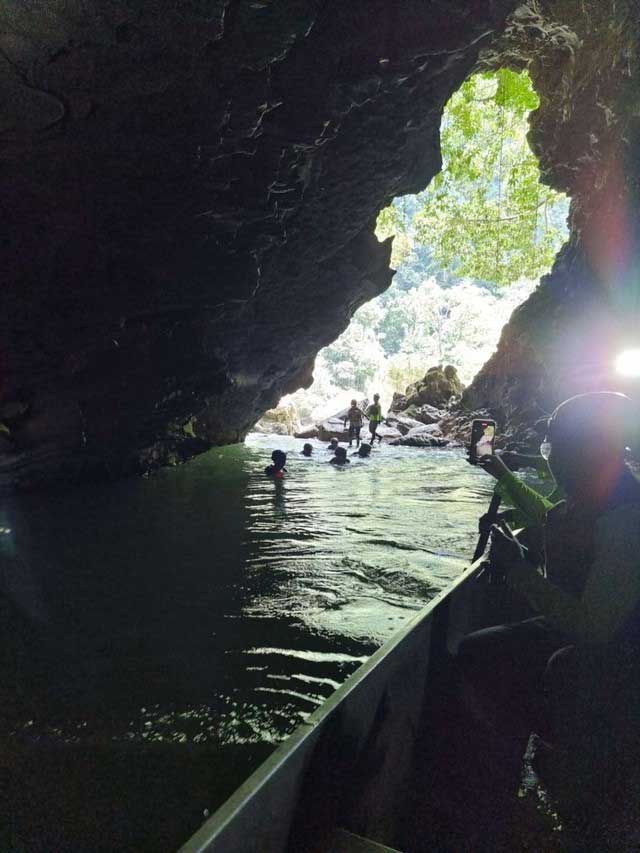 Tourists kayaking or wading through the waterfalls inside the caves