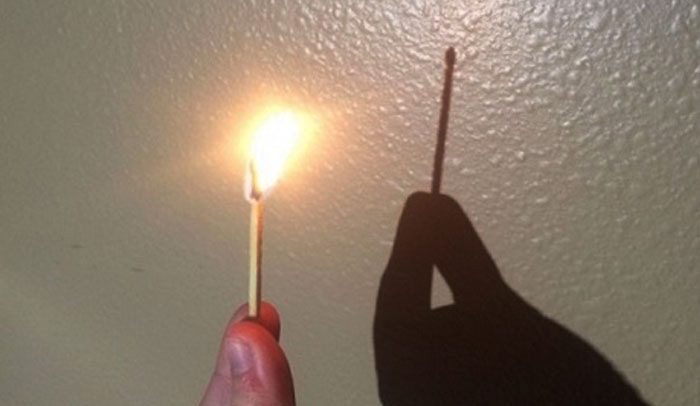 The flame of a burning matchstick does not cast a shadow on the wall.