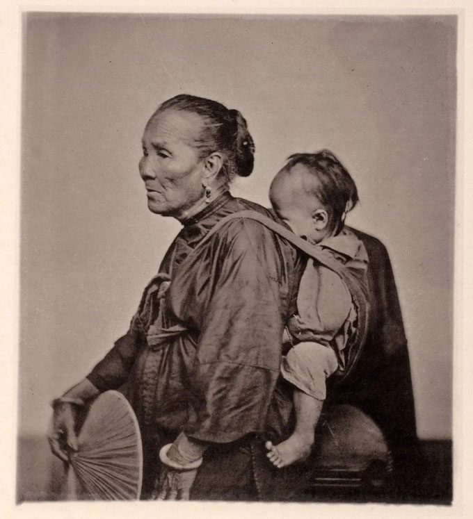 An elderly woman carrying her grandchild