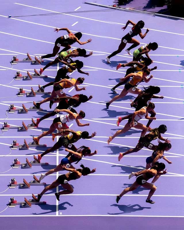 Athletes competing in the women's 100 meters on the purple track