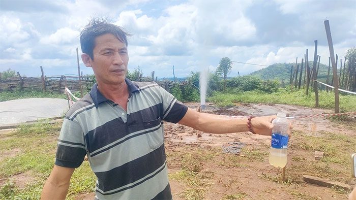 Mr. Cao Thế Sơn takes a water sample for testing, finding no unusual smell.