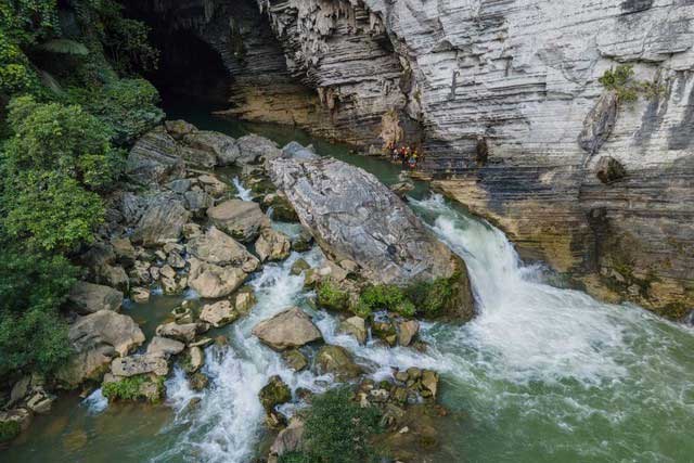 A waterfall with clear water flowing from Ken Cave, part of the Tu Lan cave system