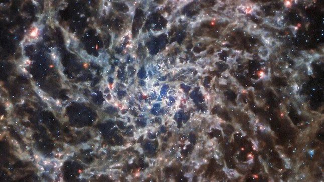 The fresh image behind the dust reveals a network of gas and stars.