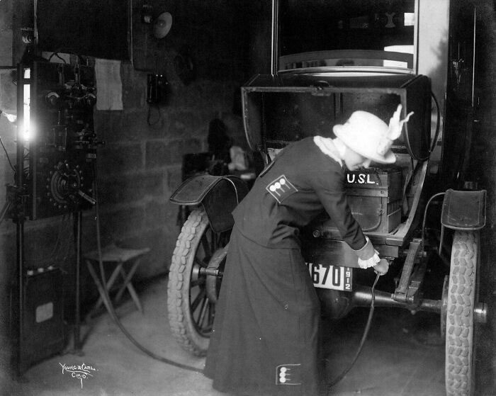 A photo from 1912 of a woman charging an electric car.