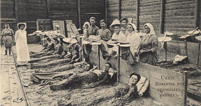 Women applying a mixture of mud and crocodile feces for skin beauty.