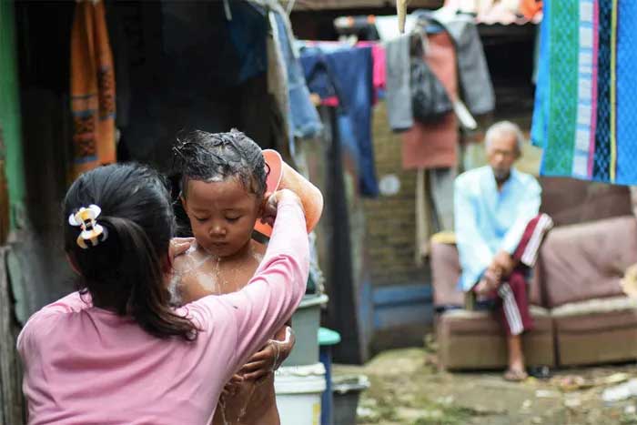 A girl bathing her sibling with water from the polluted river.