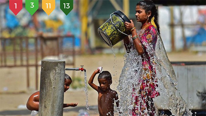 People cooling off at a public water tap in hot weather in India.