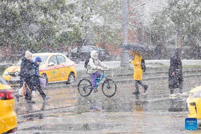 People crossing the street amidst snowfall in Moscow, Russia on May 8