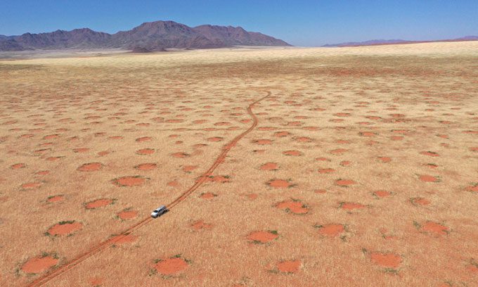 A car passing through the NamibRand Nature Reserve, one of the locations with fairy circles in Namibia.