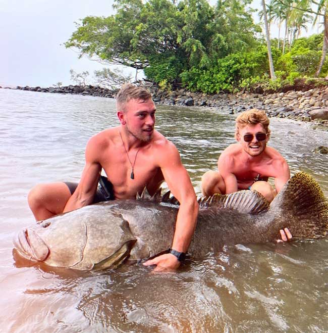 The two young men take a photo with the giant grouper before releasing it.