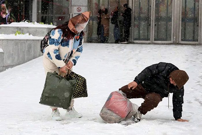 A man falls on a slope while snow falls in Beijing, China