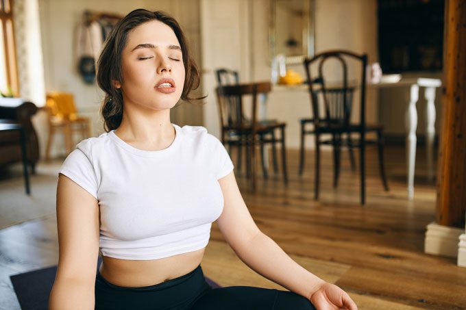 A woman practicing breathing at home in the morning.
