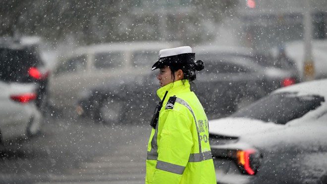 A police officer trying to manage traffic in freezing weather